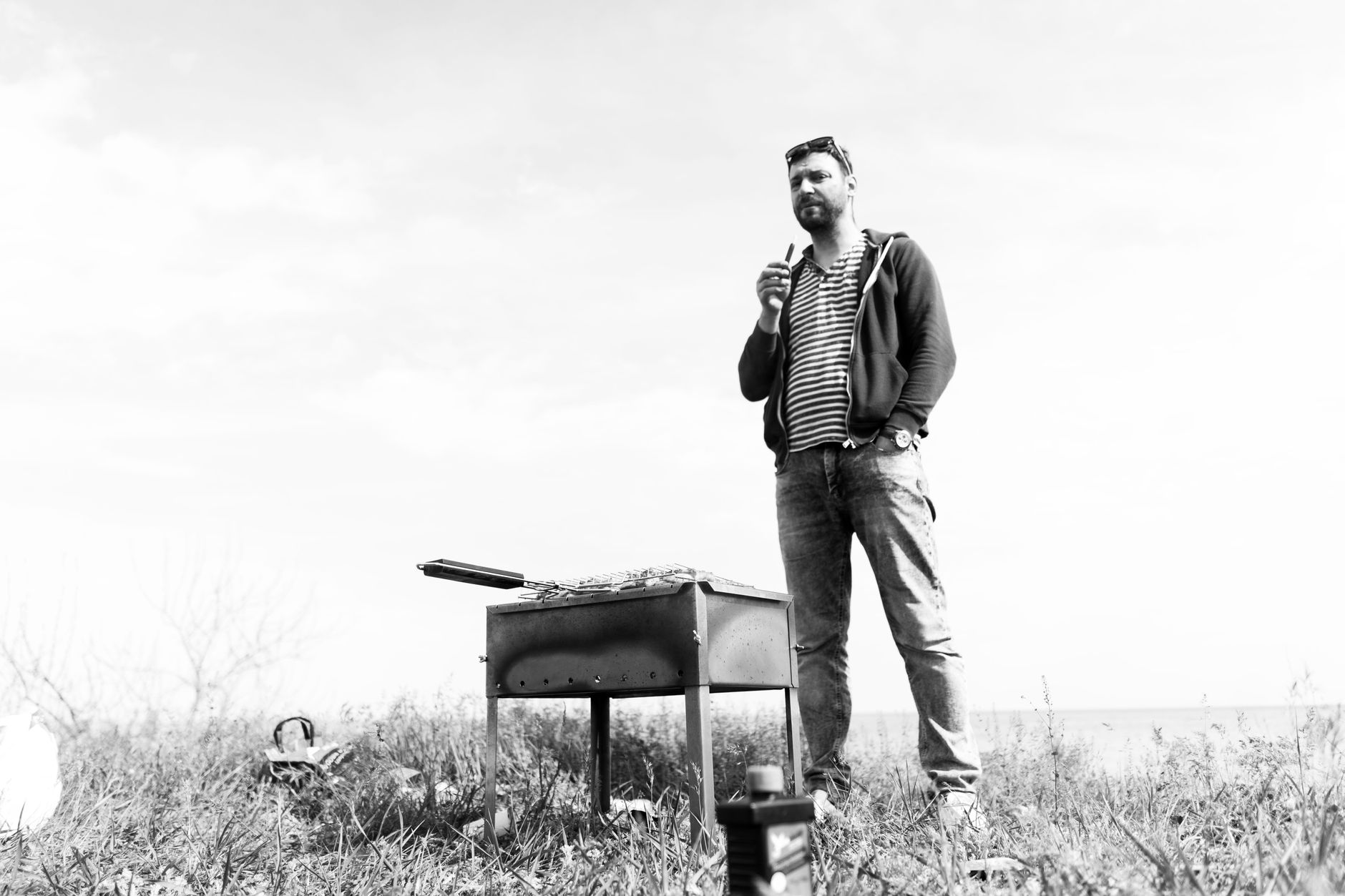 A man stands by a grill in a black and white outdoor barbecue setting.