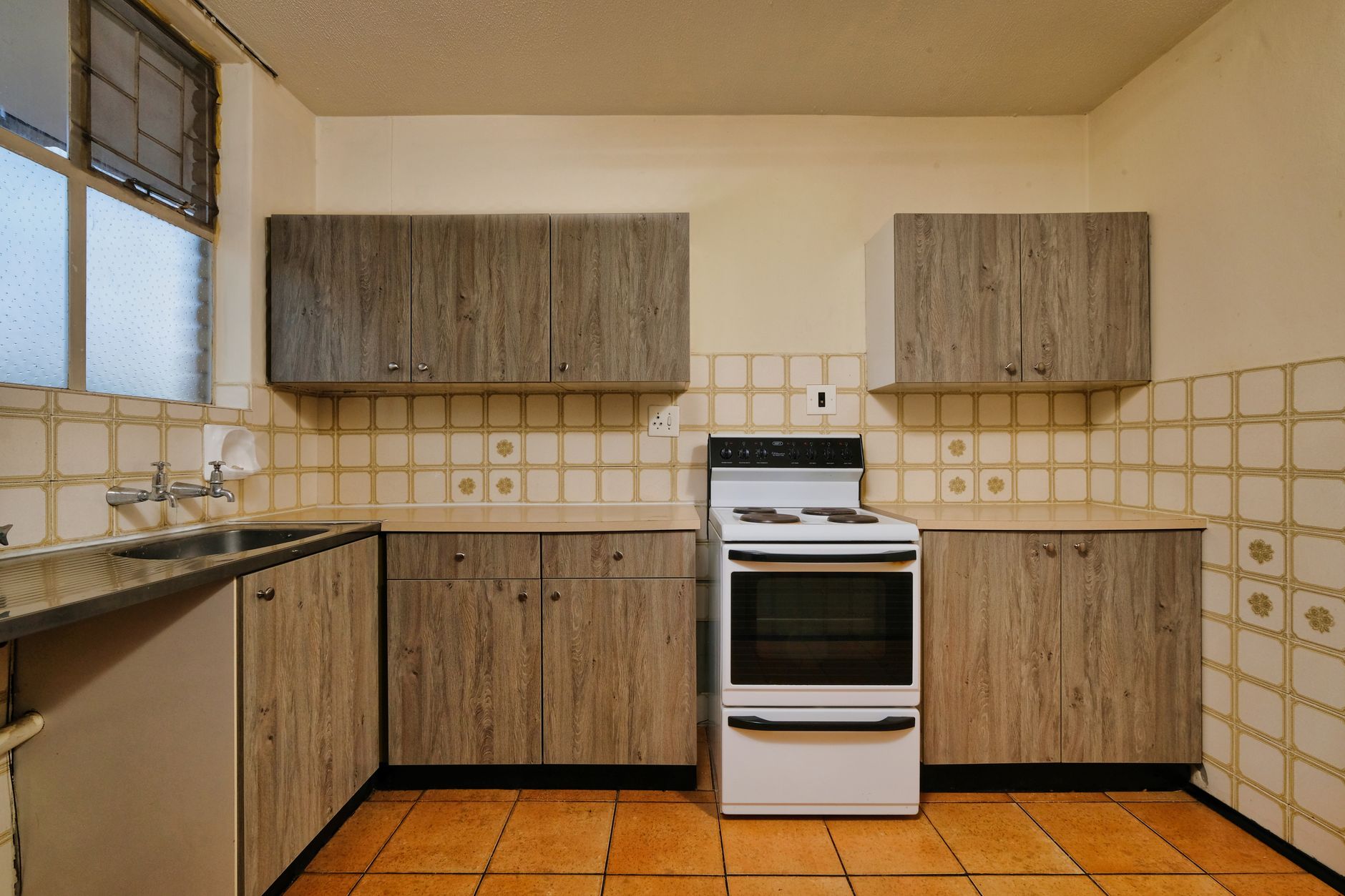 Cozy kitchen interior featuring wooden cabinets, stove, and tiled backsplash.