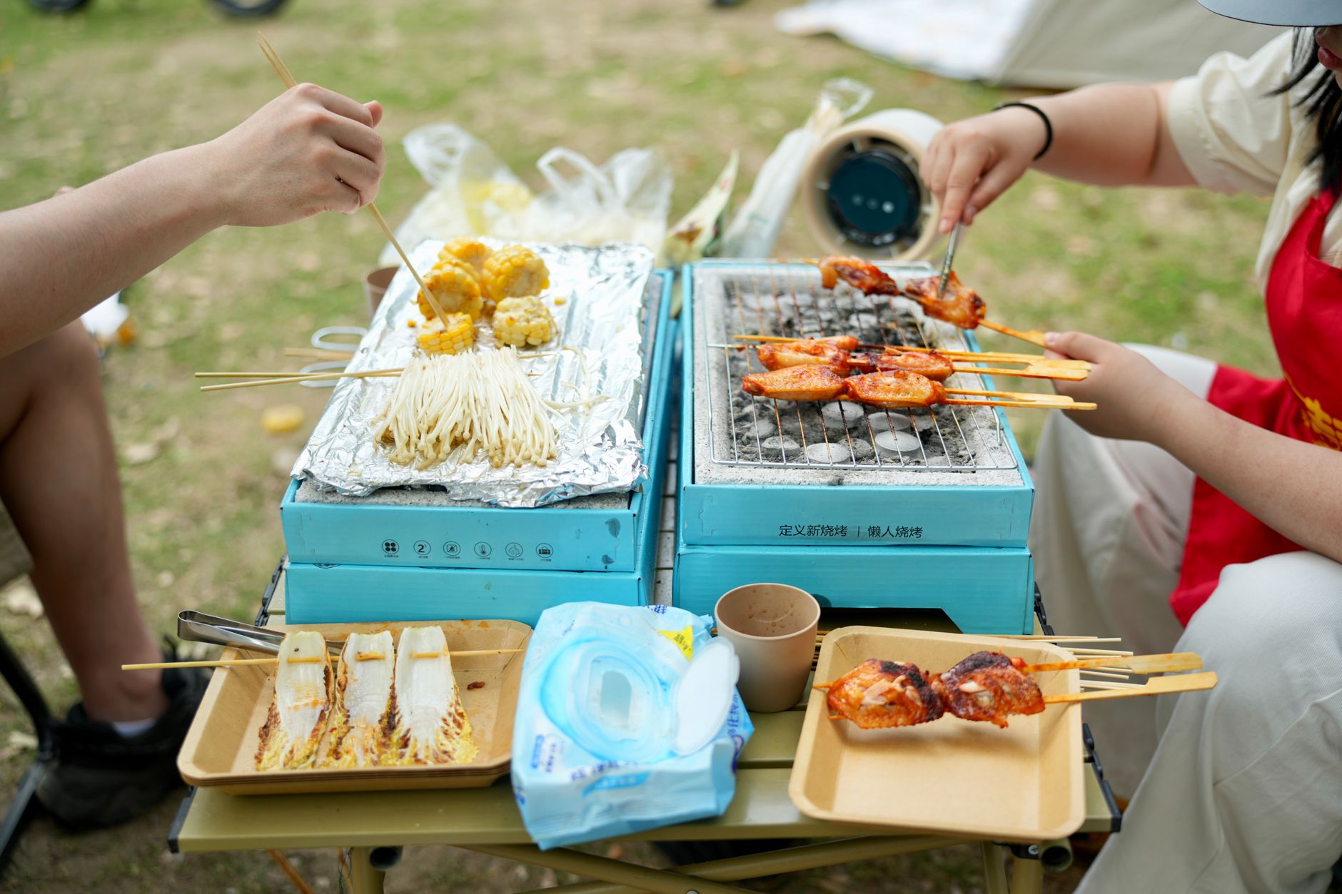 Enjoy a vibrant outdoor barbecue with skewers and snacks on portable grills.