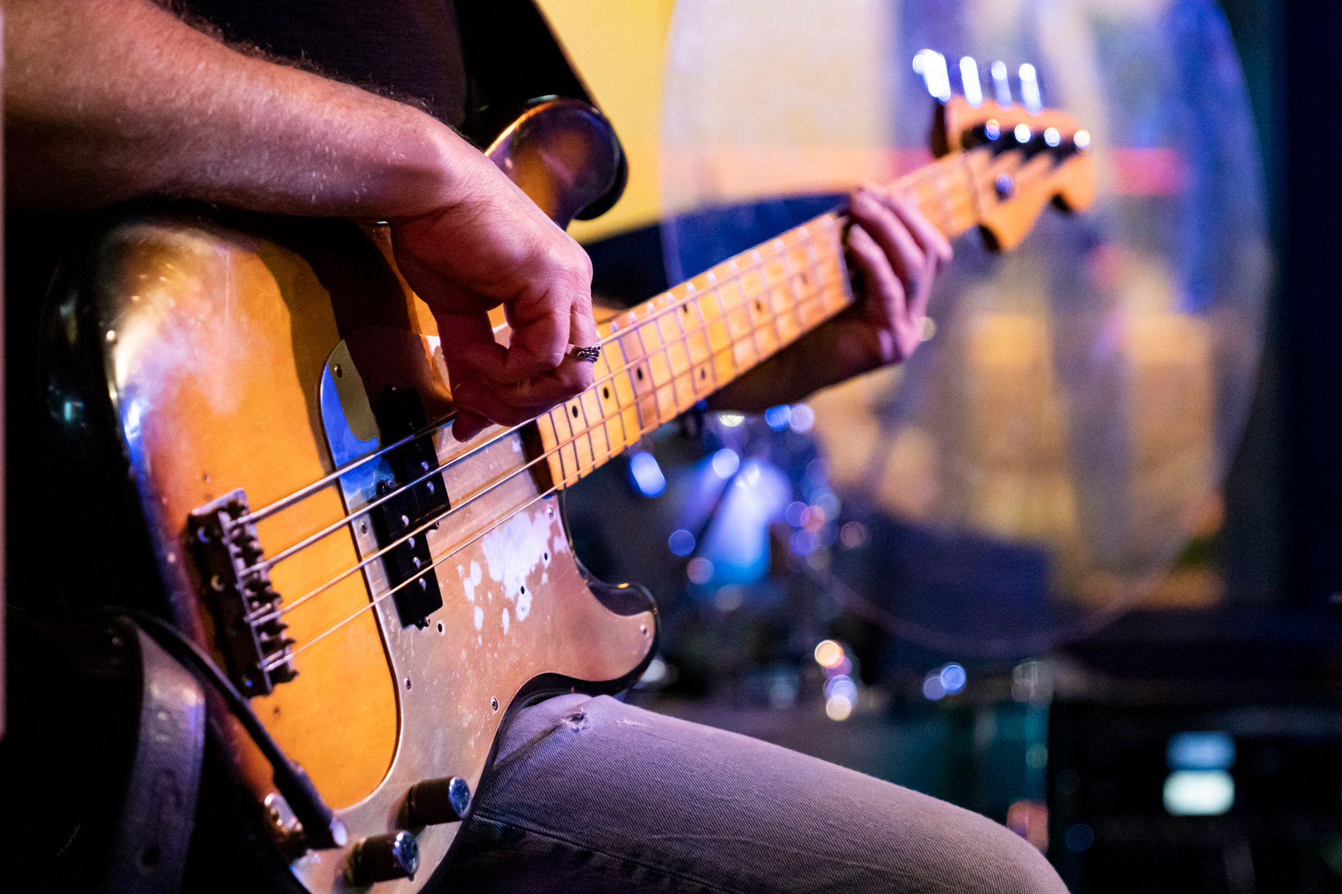 Detailed close-up of a musician playing a vintage bass guitar during a live performance.