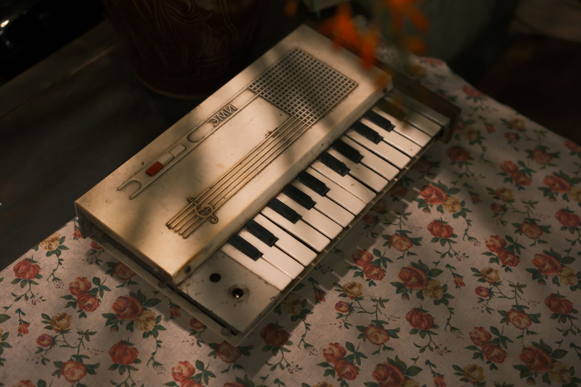 Retro electronic organ keyboard with floral table setting, capturing a vintage mood.