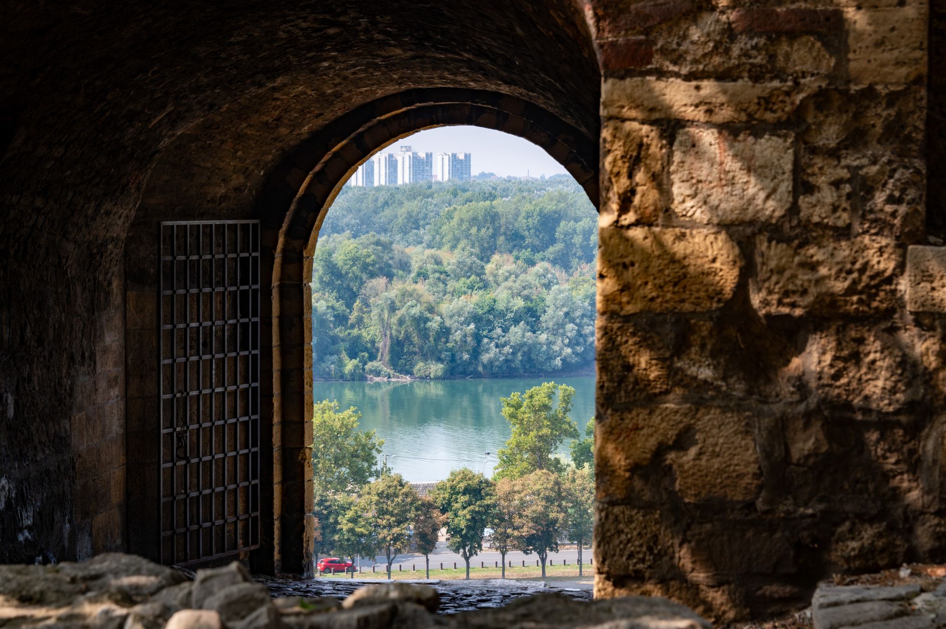 View through an ancient stone archway overlooking trees and a river in Belgrade, Serbia.