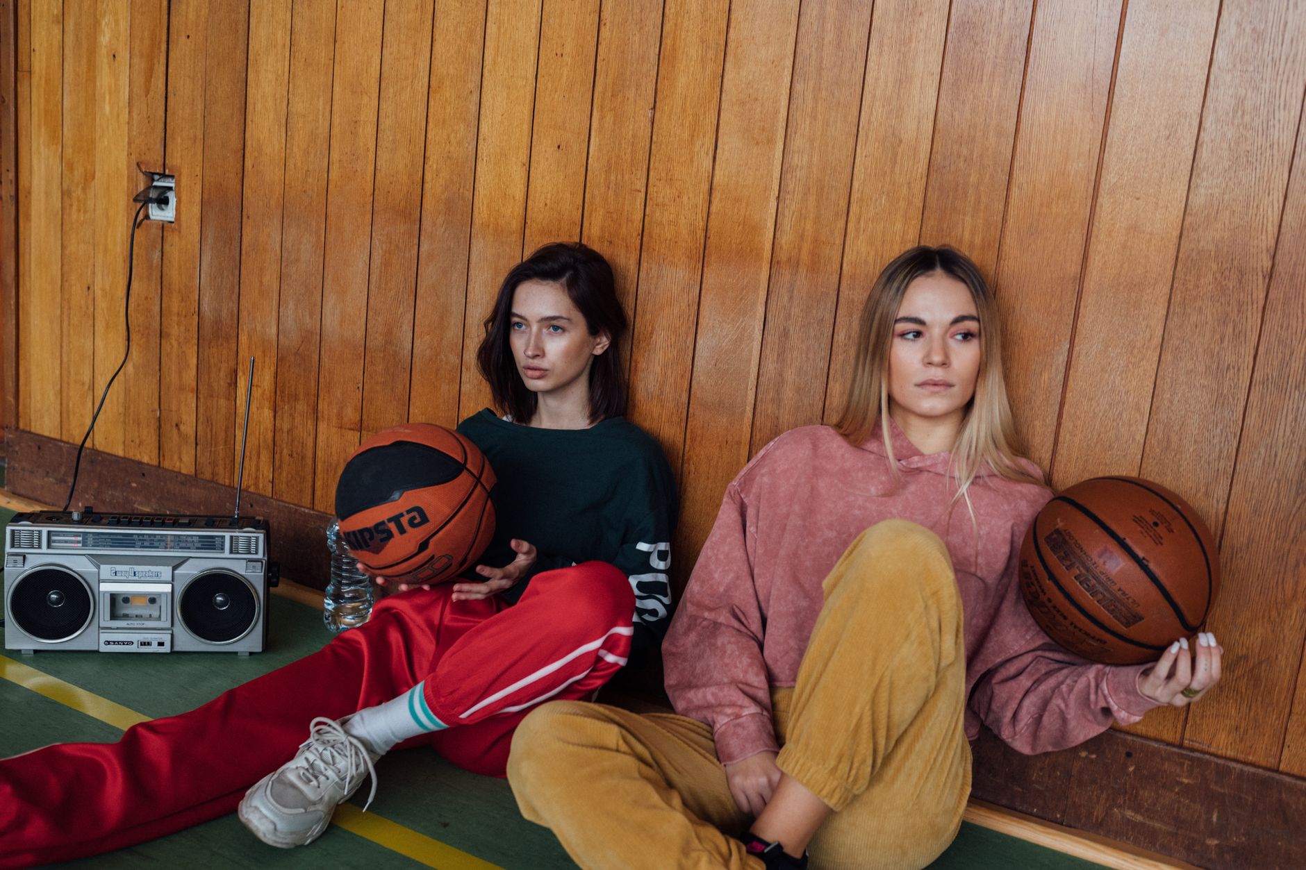 Two women with basketballs and a boombox, featuring a retro sporty aesthetic.