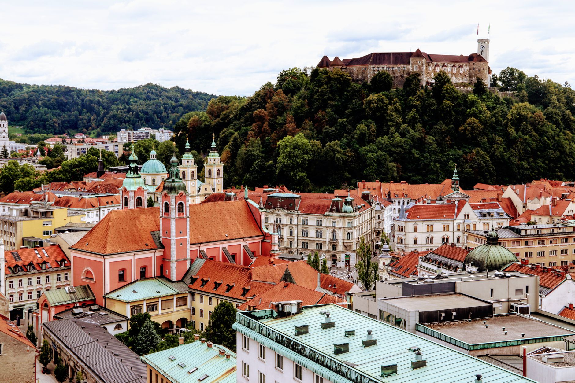 A scenic view of Ljubljana's vibrant old town with the famous castle atop a green hill.