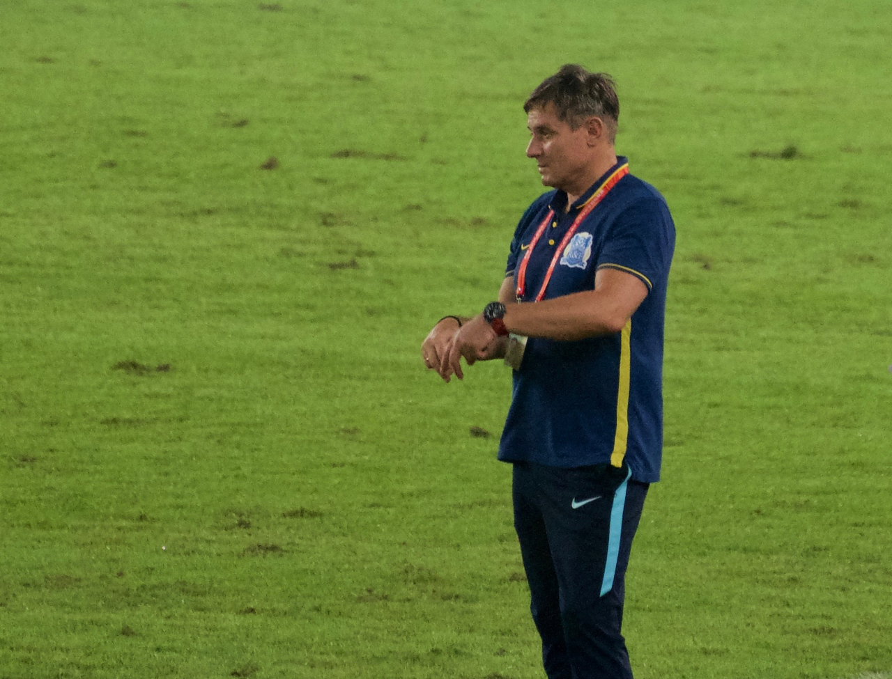 Dragan Stojković u plavoj majici stoji na travnjaku stadiona